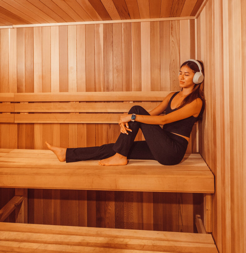 Girl sitting in Rambler Austin sauna listening to music