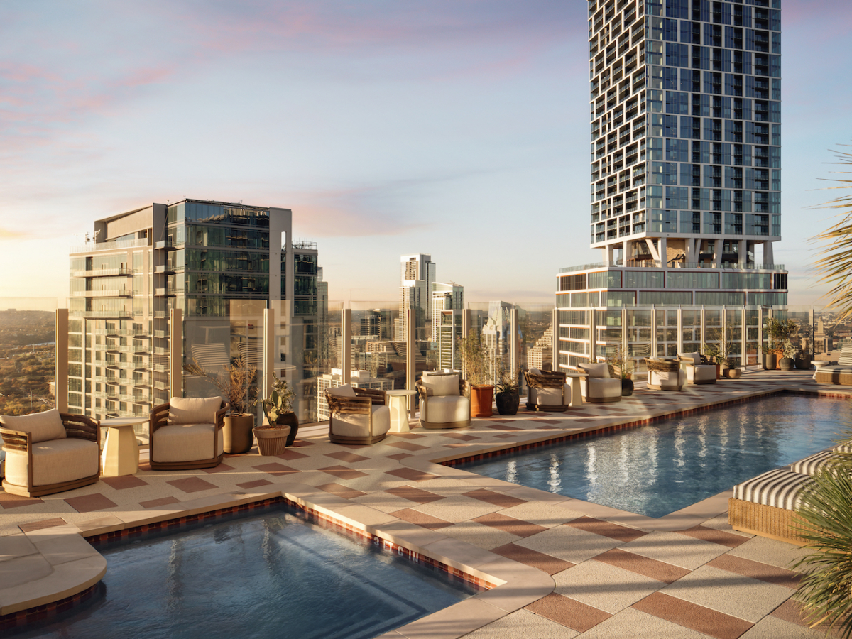 Rooftop pool area with lounge chairs and potted plants, perfect for a relaxing paseo while overlooking a city skyline of tall modern buildings at sunset. Warm light reflects off the buildings and water under partly cloudy skies.