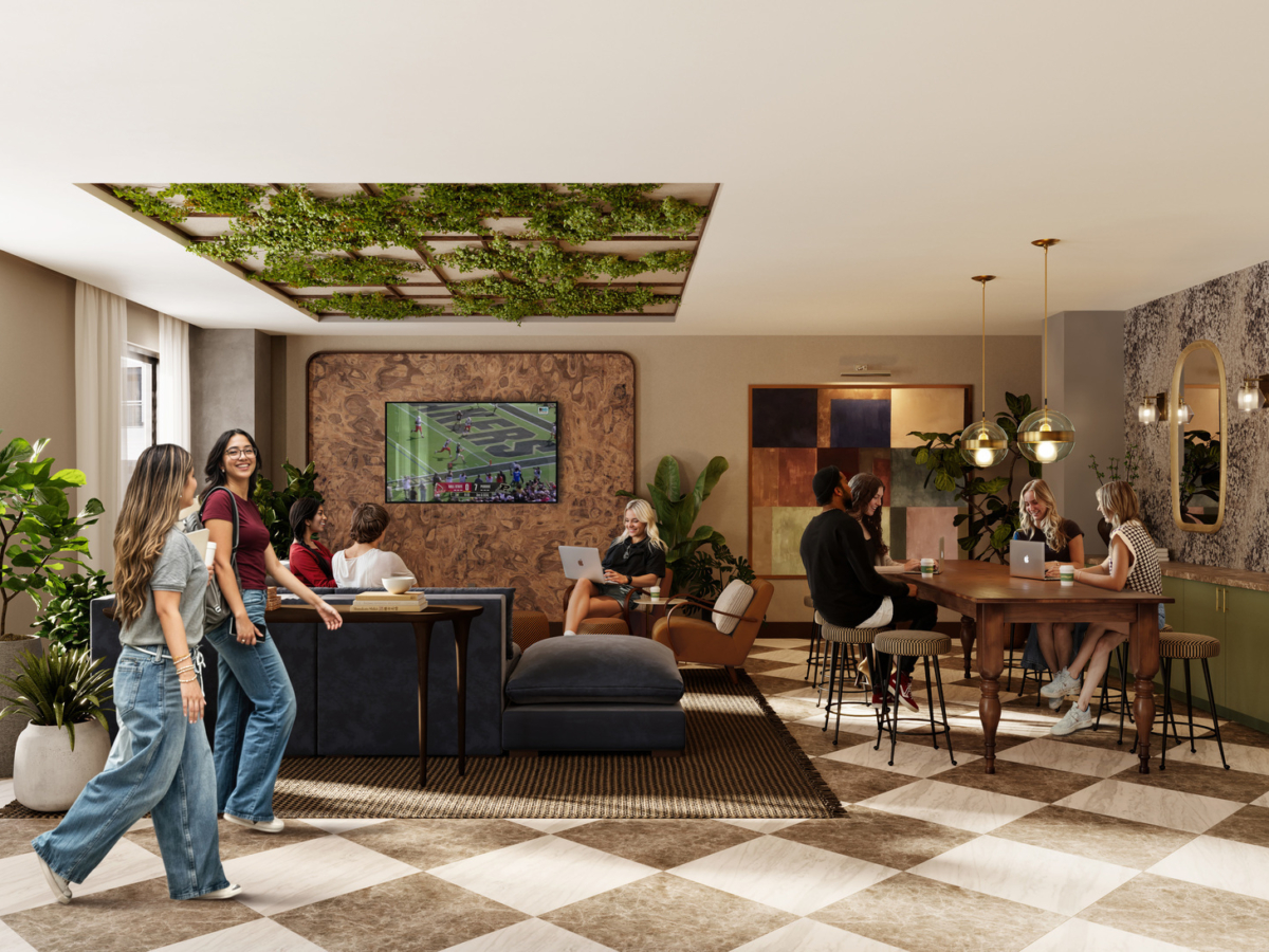 A modern lounge at Rambler Riverfront with people socializing, working on laptops, and watching a football game on a wall-mounted TV. The space features plants, large windows, stylish decor, a checkered floor, and green ceiling accents.