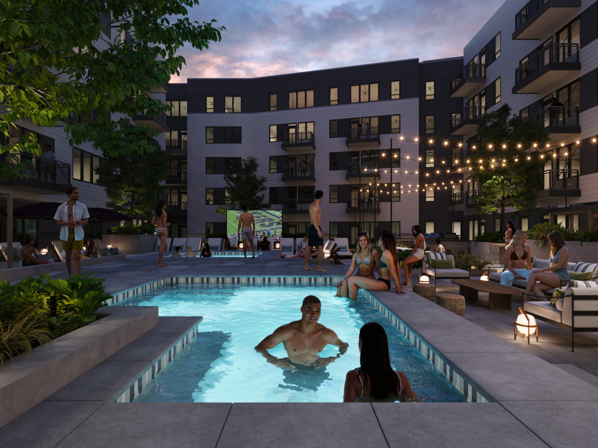 People unwind around the lit outdoor pool and hot tub at dusk in Rambler Riverfront’s modern apartment courtyard—some chat by the water, others watch a movie on an outdoor screen or socialize under glowing string lights.