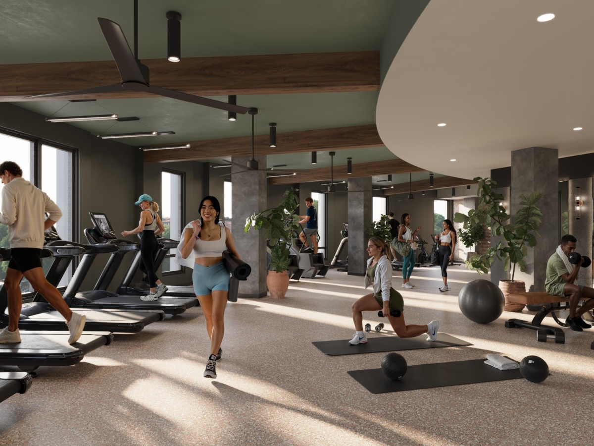 People are exercising in the modern Rambler Riverfront gym with treadmills, free weights, exercise mats, and fitness balls. The bright space features large windows, plants, and wooden accents. Some are running, stretching, or lifting weights.