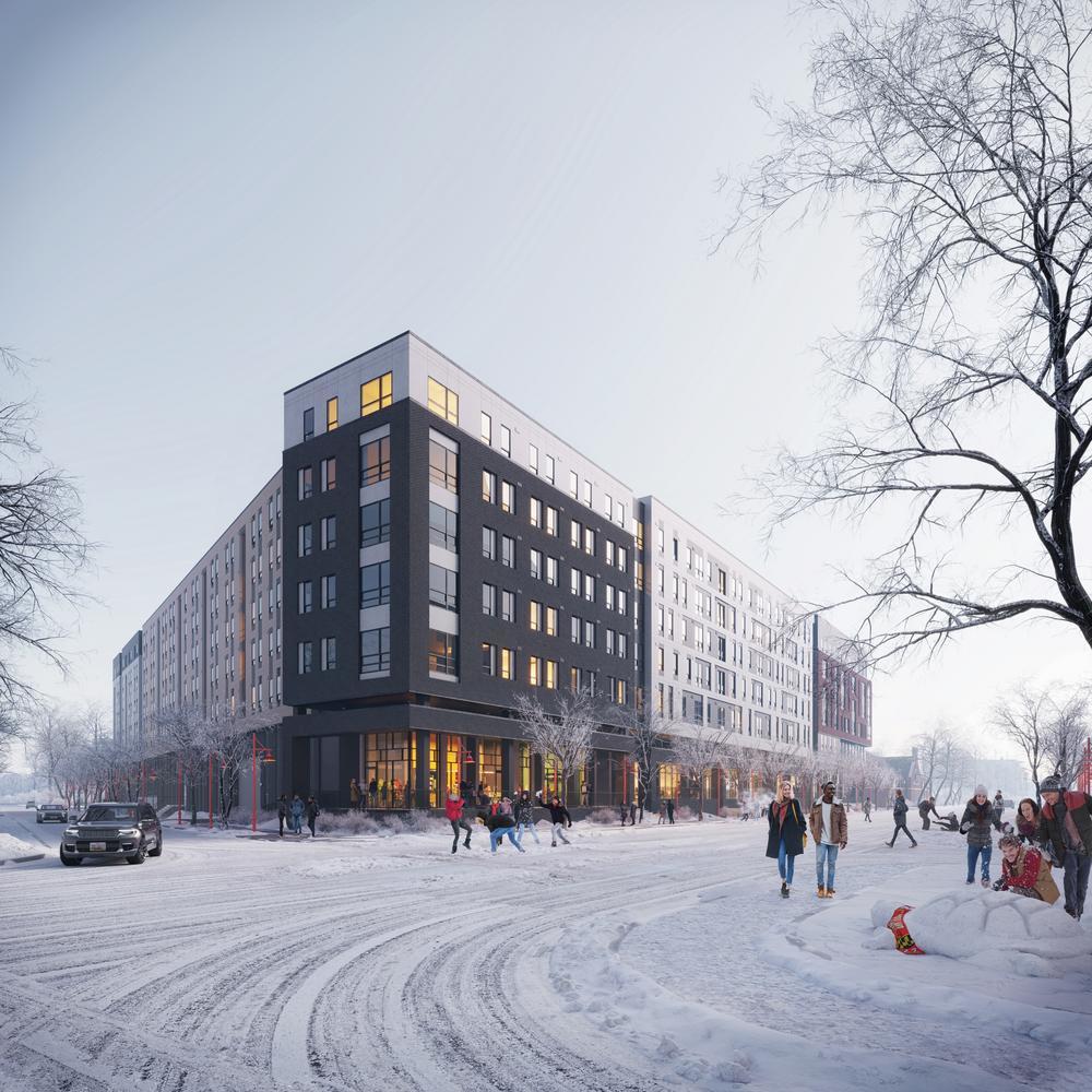 A modern multi-story apartment building on a snowy street corner near Rambler College Park. People walk and gather in winter clothing while a car drives by. Leafless trees and soft lighting evoke a cold, urban winter atmosphere.