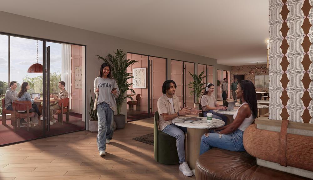 A modern lounge at Rambler Ann Arbor, with people sitting at round tables, talking and working. Large windows let in natural light. Some relax outside on the patio, while others enjoy plants and contemporary decor indoors.