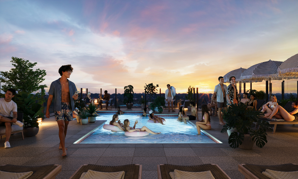 People relax by and in the Rambler Ann Arbor rooftop pool at sunset, surrounded by lounge chairs, plants, and umbrellas. Some stand and chat while others swim or sit in the water, creating a lively, social atmosphere under a colorful sky.