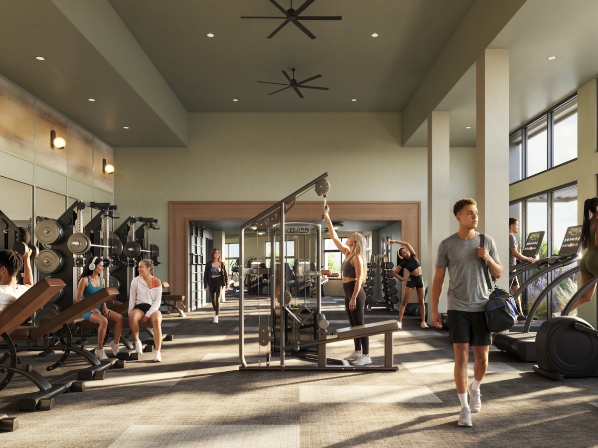 People working out in a modern gym filled with cardio machines, weight benches, and strength equipment—a convenience offered to residents of Rambler Blacksburg student housing. Large windows let in natural light, and several people use various exercise machines, enjoying the vibrant atmosphere typical of high-quality student amenities.