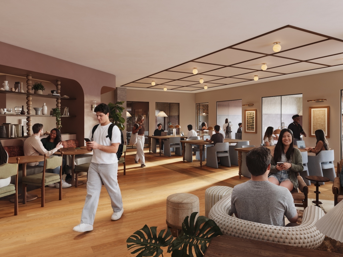 A modern, busy café near Rambler Blacksburg student housing buzzes with people sitting at tables, chatting, working on laptops, and drinking coffee. Large windows let in natural light. One person walks through the center holding a cup. The atmosphere is warm and inviting.