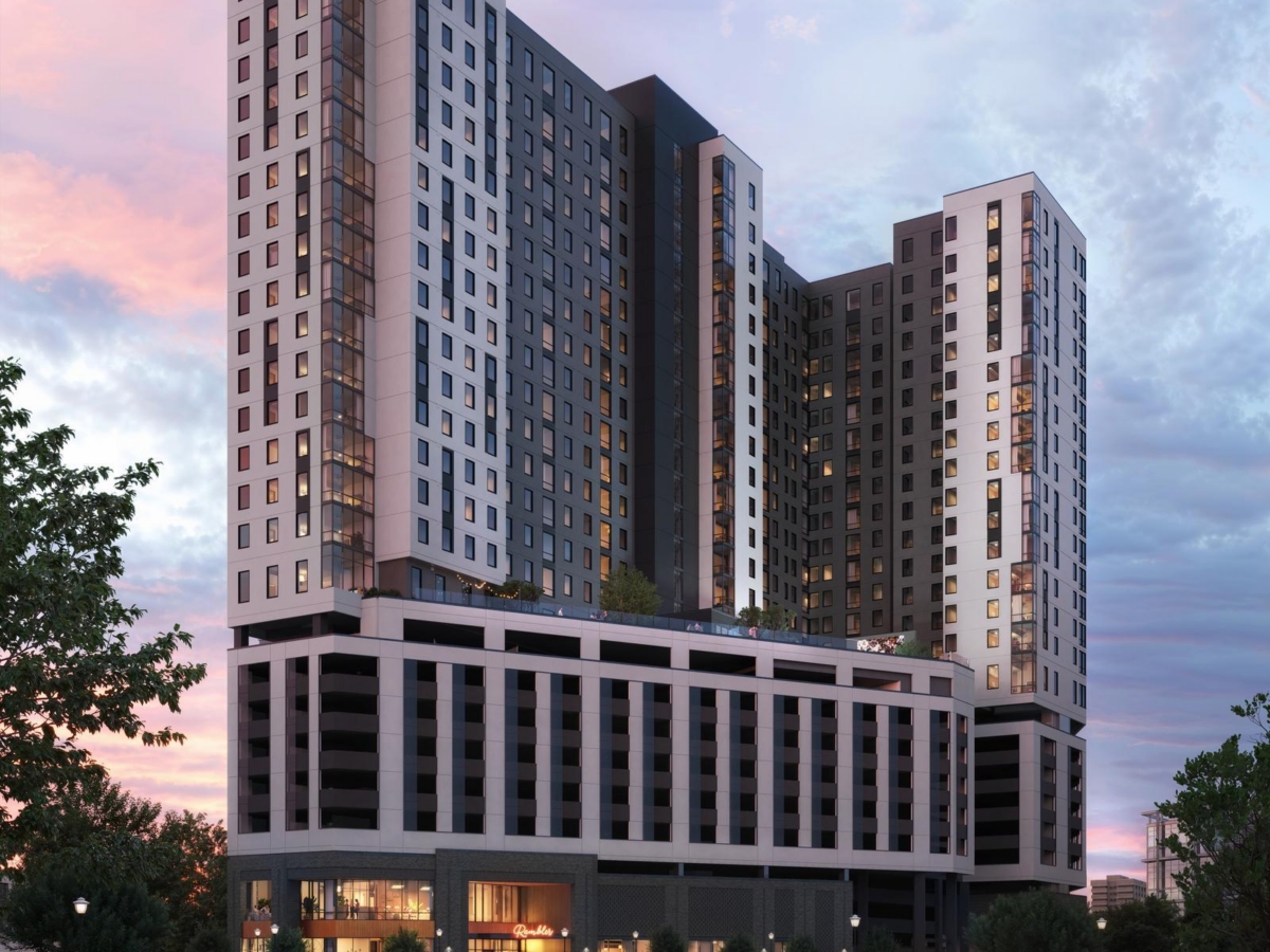 A modern high-rise Gainesville student housing apartment building at sunset, featuring large windows, a multi-story base, rooftop greenery, and people gathering in the lively plaza below among trees and lampposts.