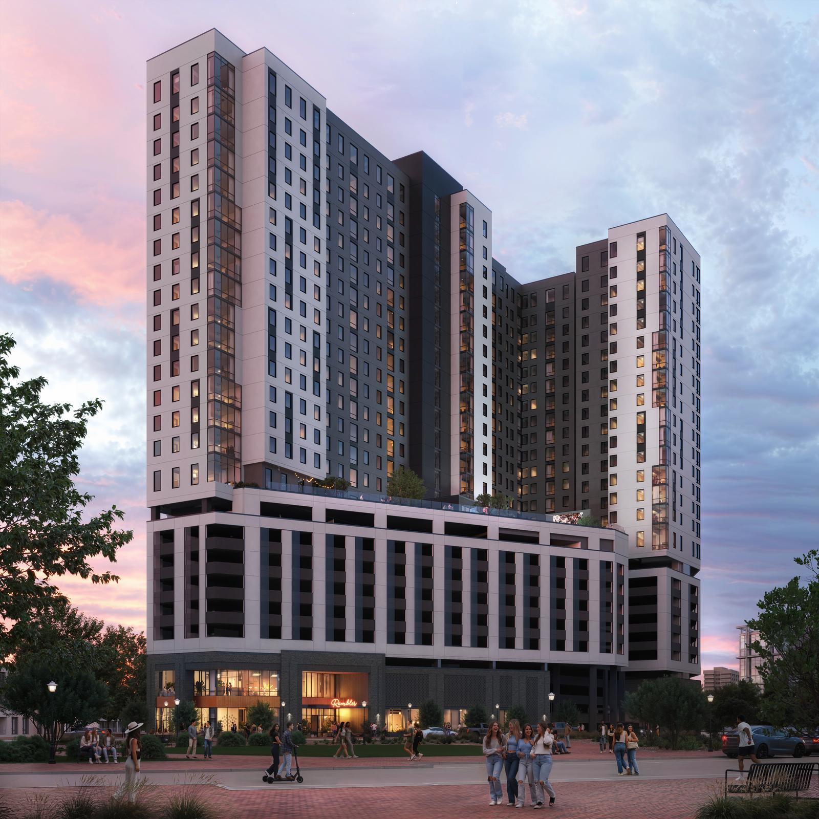 A modern high-rise Gainesville student housing apartment building at sunset, featuring large windows, a multi-story base, rooftop greenery, and people gathering in the lively plaza below among trees and lampposts.