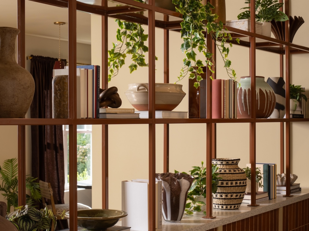 A tall metal shelving unit featuring assorted vases, books, and potted plants, set against a low tiled wall in the College Park South rambler.